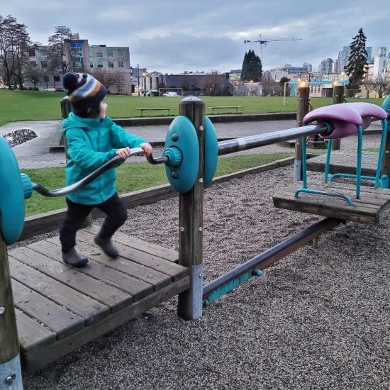 Child turning crank to move platform on monorail at Jonathan Rogers Park playground